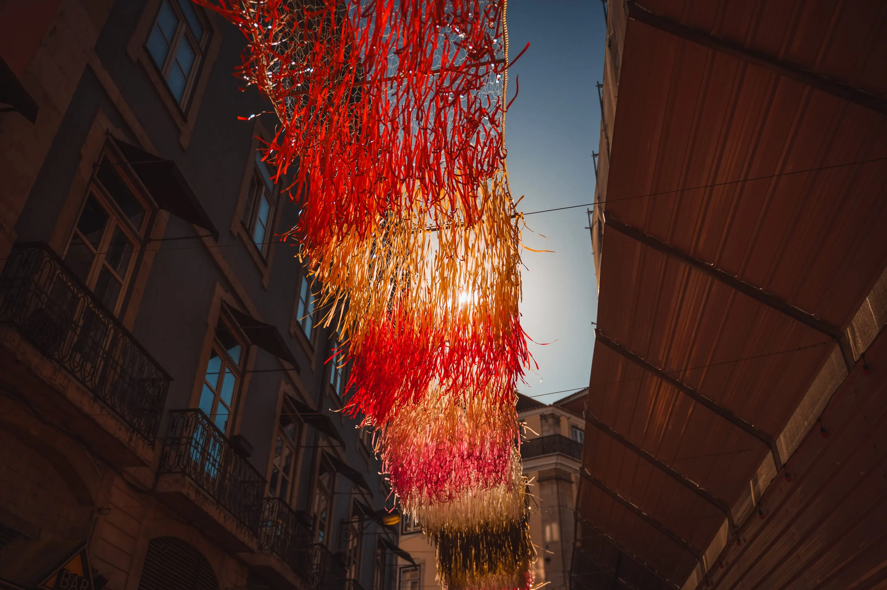 Lichtergirlanden über einer Gasse in Lissabon in der Abendsonne